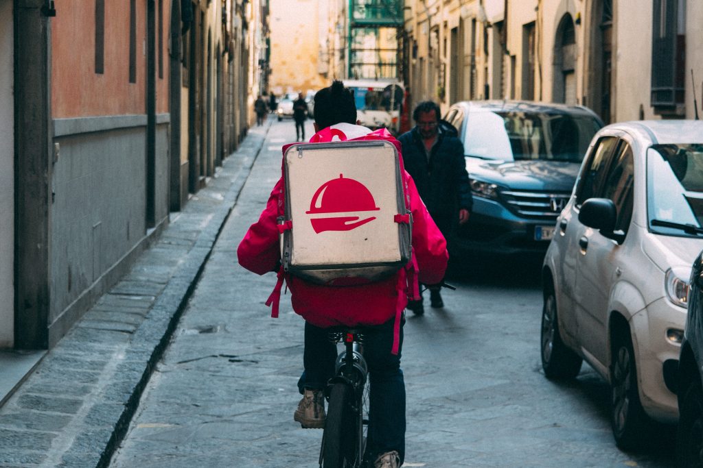 A delivery person riding a bike with a delivery box on their back