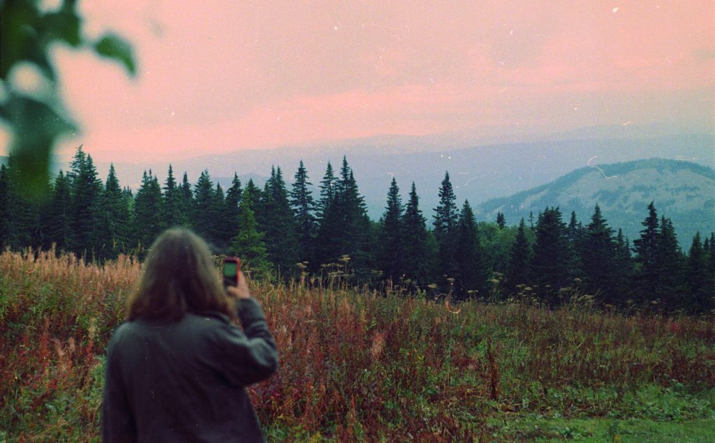 Women capturing a photo in a rural mountain field.