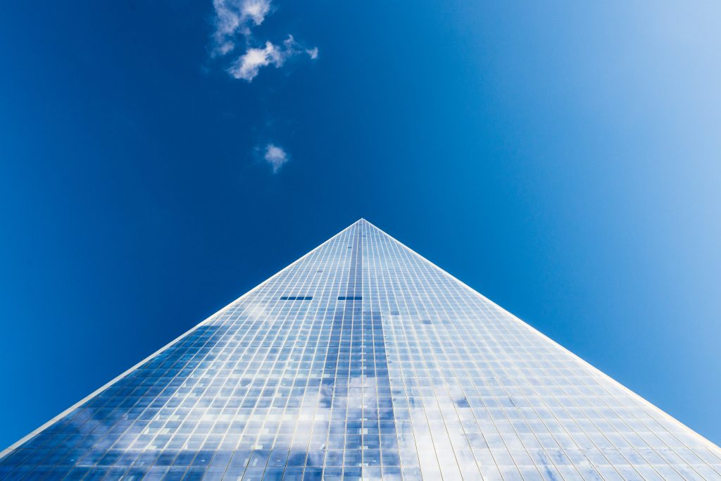 A vertical view of a building upwards towards a blue sky